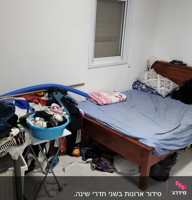 חדר מבולגן עם בגדים על המיטה וסולם בצד